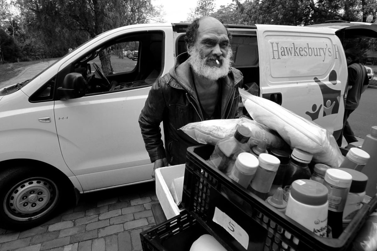 Lanz pushes a cart of food supplies from a white van towards the camera.
